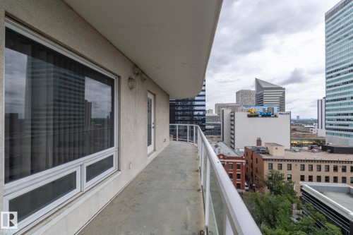 Balcony with a concrete floor, glass railing, and urban landscape backdrop - #1004 10136 104 St Nw, Edmonton, AB - Outdoor