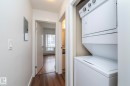 Hallway featuring wood-finish flooring, white walls, and a stacked washer and dryer - #1004 10136 104 St Nw, Edmonton, AB  - Indoor Photo Showing Laundry Room 