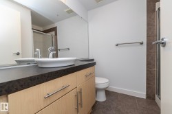 Modern vanity with a vessel sink, dark countertop, and light wood-finish cabinetry - 