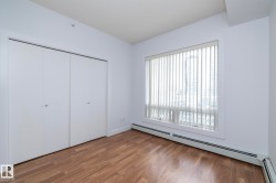 Wood-finish flooring, white bi-fold closet doors, and large window with vertical blinds - 