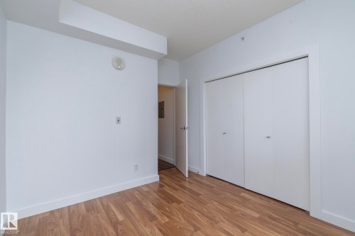 Wood-finish flooring, white walls, and a built-in closet with bi-fold doors - #1004 10136 104 St Nw, Edmonton, AB - Indoor Photo Showing Other Room