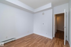 Wood-finish flooring with white baseboards, white walls, and a white interior door with a brushed nickel lever - 