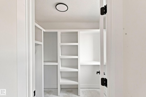 Custom built-in shelving, integrated hanging rods, and an overhead flush-mount light fixture - 1818 155 Avenue Nw, Edmonton, AB - Indoor Photo Showing Other Room