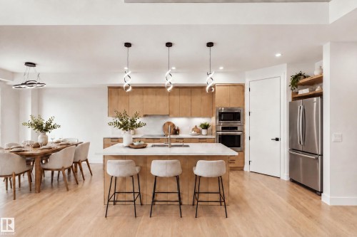 Open concept living with wood-finish flooring, light wood cabinetry, stainless steel appliances, and a kitchen island with seating - 1818 155 Avenue Nw, Edmonton, AB - Indoor