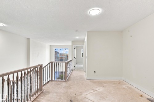 Spacious upper-level hallway featuring neutral wall finishes, recessed ceiling lighting, and a decorative metal railing overlooking the lower level - 1818 155 Avenue Nw, Edmonton, AB - Indoor Photo Showing Other Room