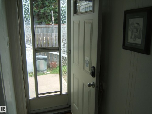 Entryway featuring a paneled door with a deadbolt and a storm door with decorative grilles - 5530 50 Street, Vegreville, AB 