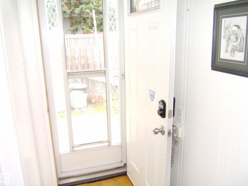 Entryway featuring a white paneled door with contemporary hardware and a glass storm door - 5530 50 Street, Vegreville, AB 