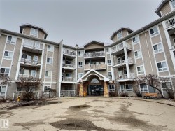 Multi-story building with neutral siding, individual balconies, and a stone-clad entrance - 