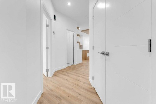 Hallway with wood-finish flooring, recessed lighting, and white paneled doors with contemporary hardware - 182 Pacific Drive, Spruce Grove, AB - Indoor Photo Showing Other Room