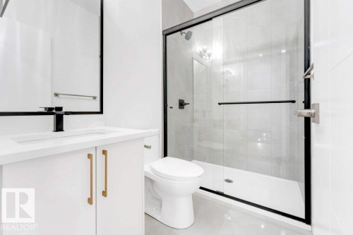 White vanity with gold-tone hardware, matte black faucet, and frameless mirror - 182 Pacific Drive, Spruce Grove, AB - Indoor Photo Showing Bathroom