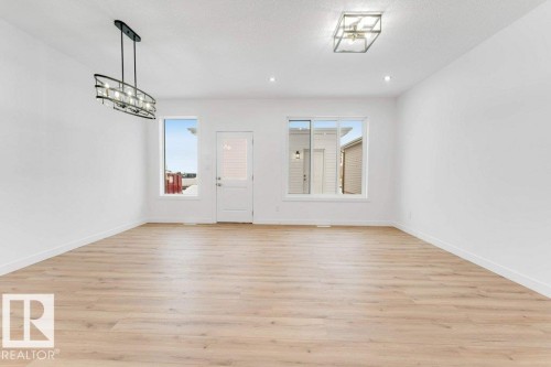 Expansive room featuring wood-finish flooring, recessed lighting, and a modern linear chandelier - 182 Pacific Drive, Spruce Grove, AB - Indoor Photo Showing Other Room