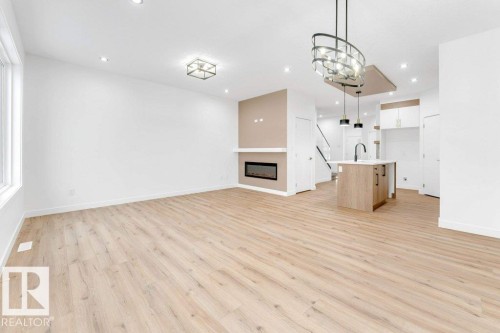 Recessed lighting, wood-finish flooring, linear fireplace, kitchen island with built-in sink, and pendant lighting - 182 Pacific Drive, Spruce Grove, AB - Indoor Photo Showing Other Room