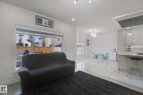 Open-concept living space with large windows, bright white walls, recessed ceiling lighting, and light-toned tile flooring - 4820 174 Avenue Nw, Edmonton, AB - Indoor