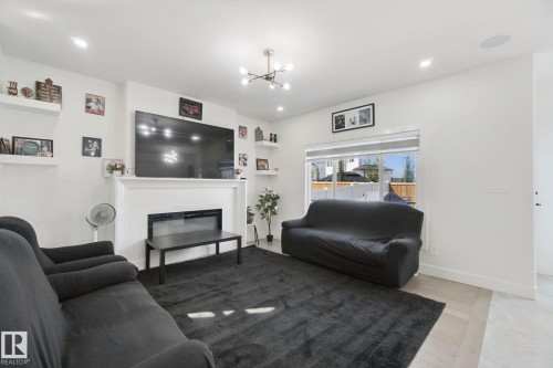 Living area featuring a contemporary fireplace, white mantel, overhead lighting, recessed lighting, and light wood-finish flooring - 4820 174 Avenue Nw, Edmonton, AB - Indoor Photo Showing Living Room With Fireplace
