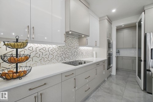 Sleek kitchen featuring white upper cabinetry, light gray lower cabinetry, and a patterned backsplash - 4820 174 Avenue Nw, Edmonton, AB - Indoor Photo Showing Kitchen With Upgraded Kitchen