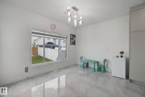 Large window with white trim, modern ceiling fixture, tile flooring, and white walls - 4820 174 Avenue Nw, Edmonton, AB - Indoor Photo Showing Other Room