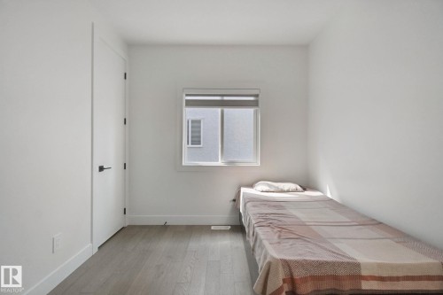 Crisp white walls, wood-finish flooring, and a window with roller shades - 4820 174 Avenue Nw, Edmonton, AB - Indoor Photo Showing Bedroom