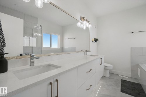 Dual vanity with integrated sinks, white cabinetry, chrome fixtures, and a spacious mirror - 4820 174 Avenue Nw, Edmonton, AB - Indoor Photo Showing Bathroom