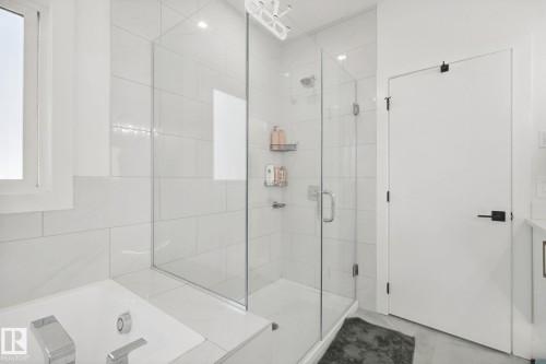 Walk-in shower with clear glass enclosure, white rectangular wall tiles, and chrome fixtures - 4820 174 Avenue Nw, Edmonton, AB - Indoor Photo Showing Bathroom