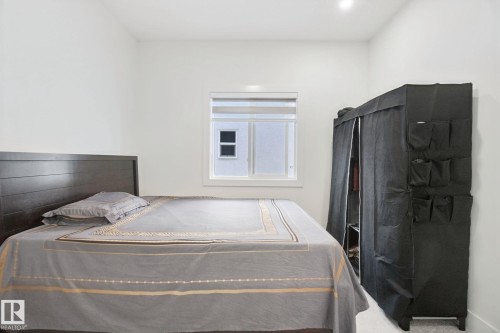Bright bedroom with horizontal wood-finish headboard, generous window with natural light, and ample closet storage featuring interior organization systems - 4820 174 Avenue Nw, Edmonton, AB - Indoor Photo Showing Bedroom