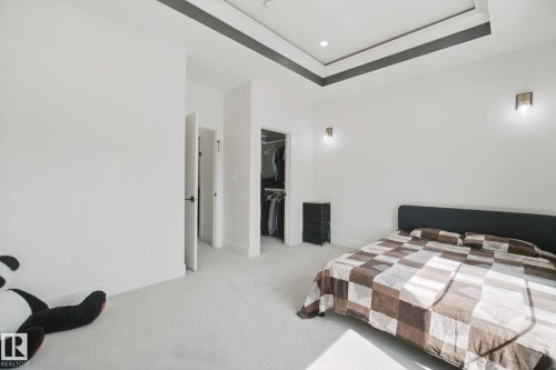 Tray ceiling with accent trim, wall-mounted light fixtures, built-in recessed lighting, and carpet flooring - 4820 174 Avenue Nw, Edmonton, AB - Indoor Photo Showing Bedroom