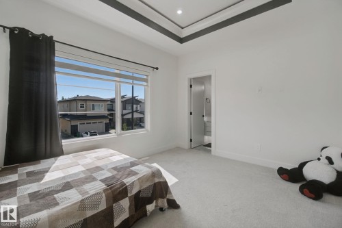 Tray ceiling with recessed lighting, large window, light-colored carpet, white walls, and a white door with black hardware - 4820 174 Avenue Nw, Edmonton, AB - Indoor Photo Showing Bedroom