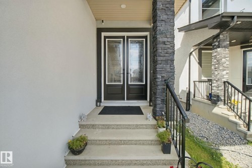 Stucco exterior with stone veneer accents, double entry doors with decorative glass, and a black wrought iron railing - 4820 174 Avenue Nw, Edmonton, AB - Outdoor