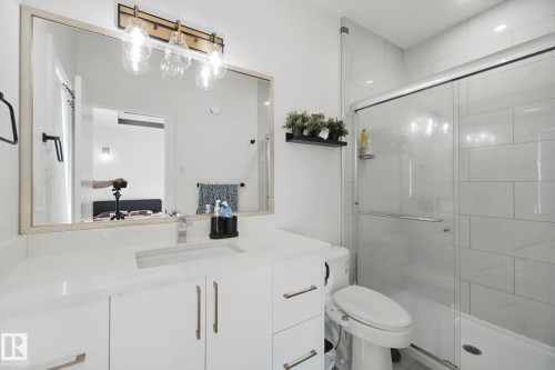 White vanity with contemporary pull hardware, integrated rectangular sink, and a framed mirror - 4820 174 Avenue Nw, Edmonton, AB - Indoor Photo Showing Bathroom