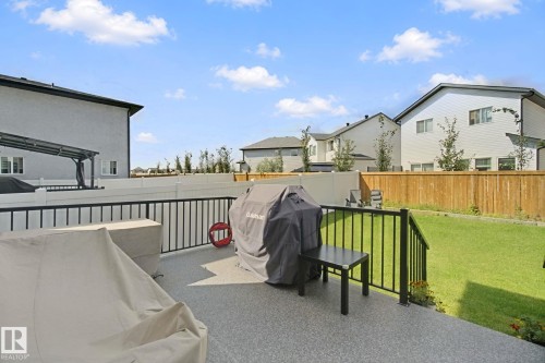 Expansive paved patio with black metal railings, leading to a generously sized lawn - 4820 174 Avenue Nw, Edmonton, AB - Outdoor