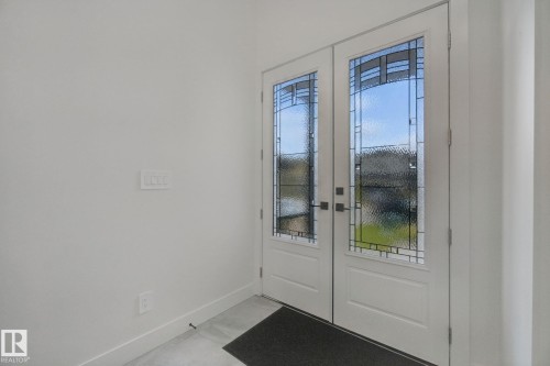 Double entry doors with decorative glass panels and matte black hardware - 4820 174 Avenue Nw, Edmonton, AB - Indoor Photo Showing Other Room