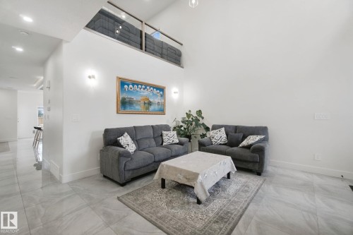 High vaulted ceilings, recessed lighting, wall-mounted sconces, and a second-level open-concept area with a glass railing - 4820 174 Avenue Nw, Edmonton, AB - Indoor Photo Showing Living Room