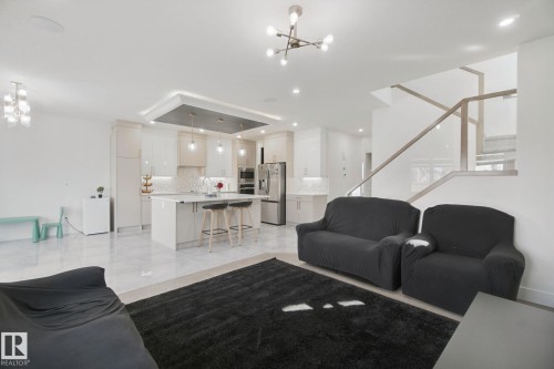Gourmet kitchen with stainless steel appliances, large island with seating, and pendant lighting - 4820 174 Avenue Nw, Edmonton, AB - Indoor Photo Showing Living Room