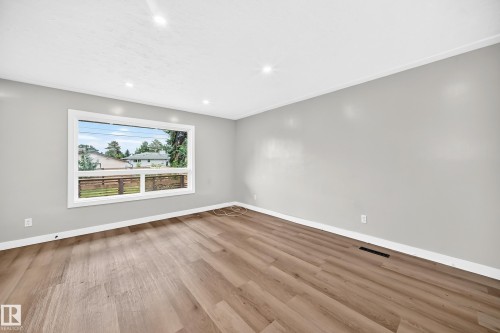 Spacious room featuring wood-finish flooring, light grey painted walls, white trim, recessed lighting, and a large window - 7603 130 Avenue Nw, Edmonton, AB - Indoor Photo Showing Other Room