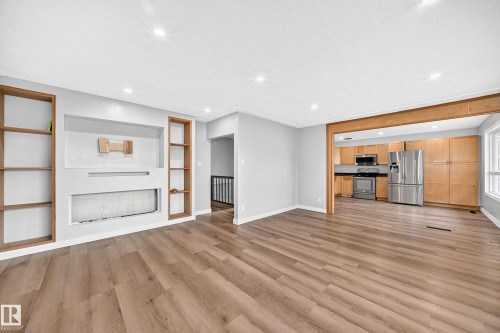 Spacious living area featuring wood-finish flooring, recessed lighting, and built-in shelving - 7603 130 Avenue Nw, Edmonton, AB - Indoor Photo Showing Other Room
