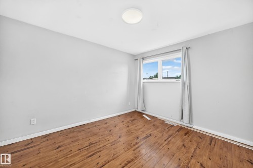 Wood-finish flooring, neutral wall tones, and a window with natural light - 7603 130 Avenue Nw, Edmonton, AB - Indoor Photo Showing Other Room