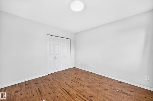 Wood-finish flooring, white walls, bi-fold closet doors, and a ceiling-mounted light fixture - 7603 130 Avenue Nw, Edmonton, AB - Indoor Photo Showing Other Room