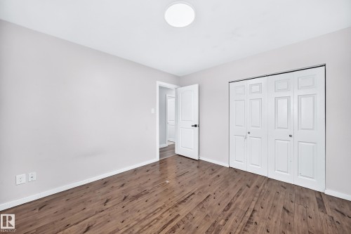 Wood-finish flooring, neutral wall tones, bi-fold closet doors, white panel doors, and a flush mount ceiling light - 7603 130 Avenue Nw, Edmonton, AB - Indoor Photo Showing Other Room