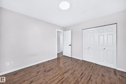Wood-finish flooring, neutral wall tones, bi-fold closet doors, white panel doors, and a flush mount ceiling light - 