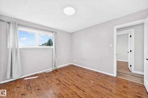 Wood-finish flooring with light-toned walls and a flush-mount ceiling light - 7603 130 Avenue Nw, Edmonton, AB - Indoor Photo Showing Other Room