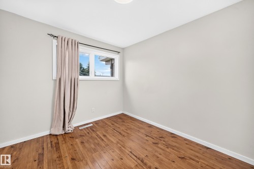 Wood-finish flooring, white trim, light gray walls, and a white window frame - 7603 130 Avenue Nw, Edmonton, AB - Indoor Photo Showing Other Room