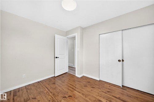 Spacious bedroom with warm wood-finish flooring, white bi-fold closet doors, and abundant natural light from recessed ceiling fixtures - 7603 130 Avenue Nw, Edmonton, AB - Indoor Photo Showing Other Room