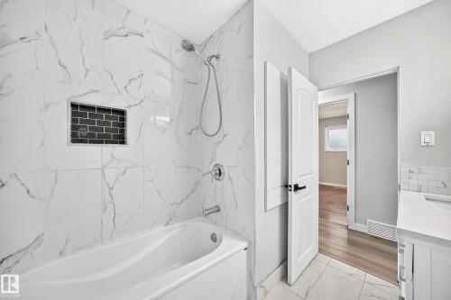 Bathtub with large format marble-look tile surround and an integrated shower niche - 7603 130 Avenue Nw, Edmonton, AB - Indoor Photo Showing Bathroom