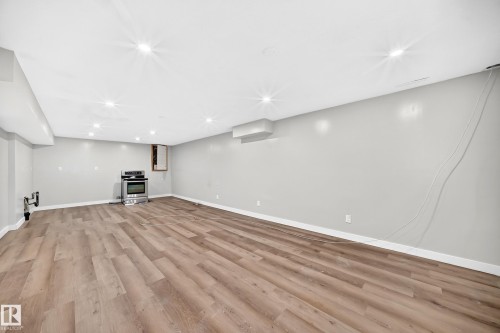Spacious room featuring wood-finish flooring, recessed lighting, neutral wall paint, and a stainless steel range - 7603 130 Avenue Nw, Edmonton, AB - Indoor Photo Showing Other Room