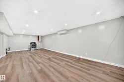 Spacious room featuring wood-finish flooring, recessed lighting, neutral wall paint, and a stainless steel range - 