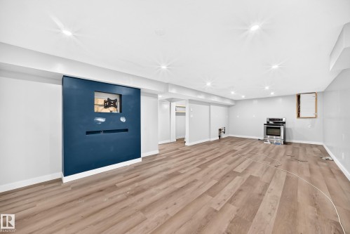 Recessed lighting, wood-finish flooring, built-in wall feature, stainless steel range, and light gray wall paint - 7603 130 Avenue Nw, Edmonton, AB - Indoor With Fireplace