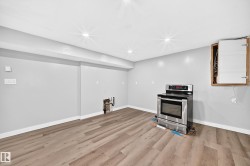 Recessed lighting, wood-finish flooring, light gray wall color, white trim, stainless steel electric range - 
