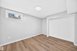 Recessed wall alcove, wood-finish flooring, white trim, single window, and a flush-mount ceiling light - 