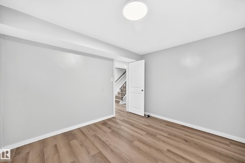 Recessed ceiling with integrated lighting, wood-finish flooring, light gray wall paint, and a white interior door - 7603 130 Avenue Nw, Edmonton, AB - Indoor Photo Showing Other Room