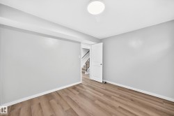 Recessed ceiling with integrated lighting, wood-finish flooring, light gray wall paint, and a white interior door - 