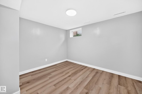 White ceiling with a flush-mount circular light fixture, light gray walls, wood-finish flooring, and a single window - 7603 130 Avenue Nw, Edmonton, AB - Indoor Photo Showing Other Room